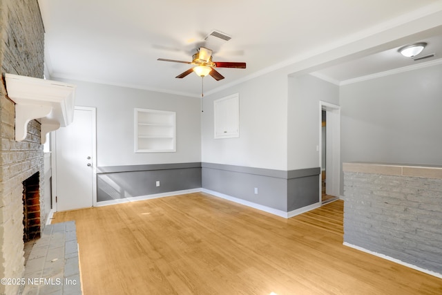 unfurnished living room featuring a fireplace, ornamental molding, ceiling fan, and light wood-type flooring