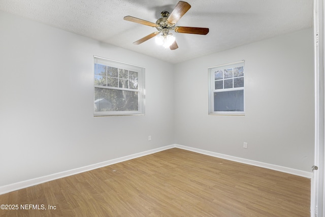 empty room with ceiling fan, wood-type flooring, and a textured ceiling