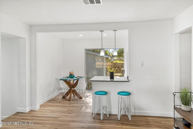 dining space with light hardwood / wood-style floors and a textured ceiling