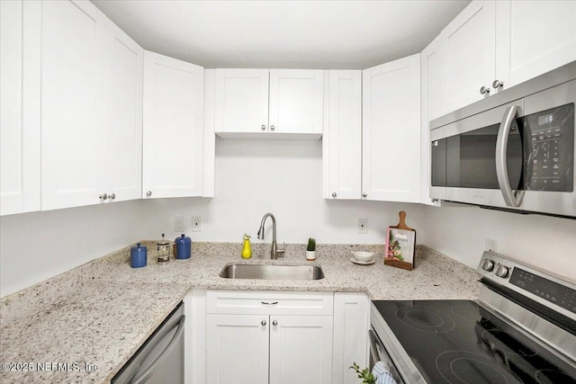 kitchen featuring light stone counters, appliances with stainless steel finishes, sink, and white cabinets