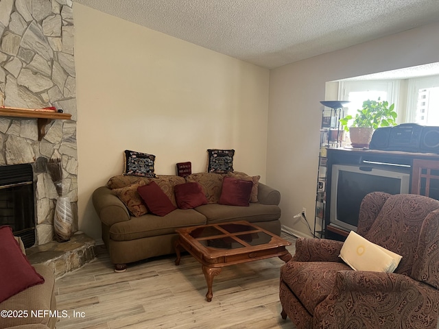 living room featuring a fireplace, a textured ceiling, and light wood-type flooring