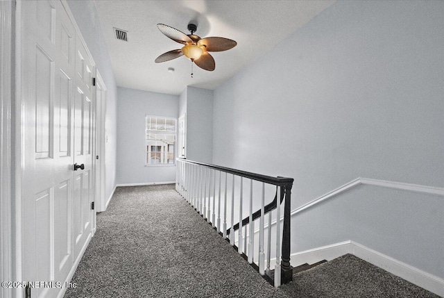 corridor featuring dark colored carpet and a textured ceiling