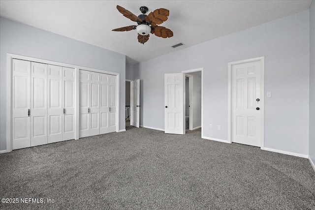 unfurnished bedroom featuring multiple closets, ceiling fan, and dark colored carpet