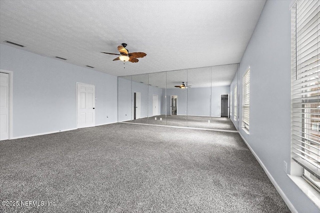 empty room featuring ceiling fan, carpet, and a textured ceiling