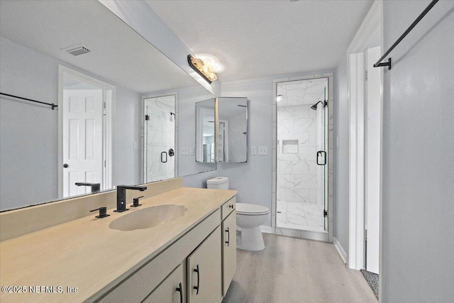 bathroom with toilet, a textured ceiling, vanity, a shower with door, and hardwood / wood-style floors