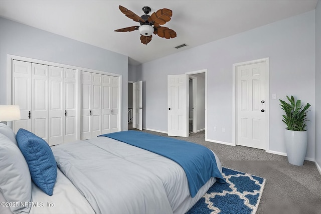 bedroom featuring multiple closets, dark carpet, and ceiling fan