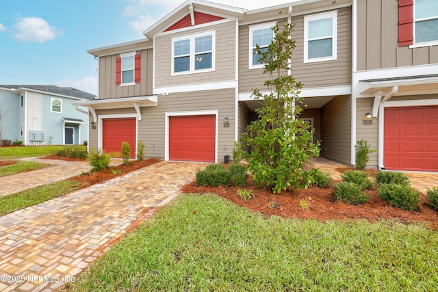 townhome / multi-family property featuring a garage and a front lawn