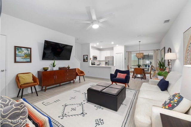 living room with ceiling fan and light hardwood / wood-style floors