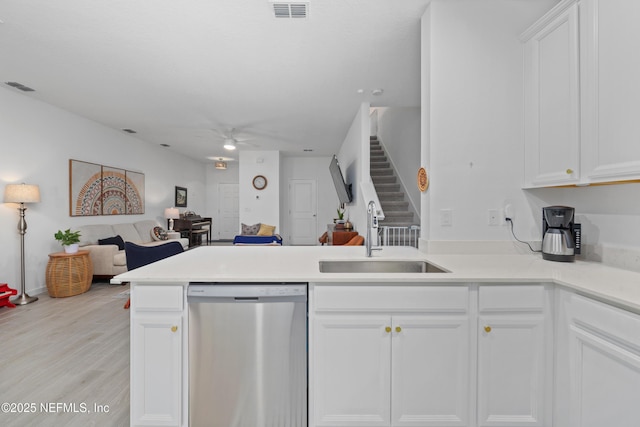 kitchen featuring dishwasher, sink, white cabinets, and kitchen peninsula