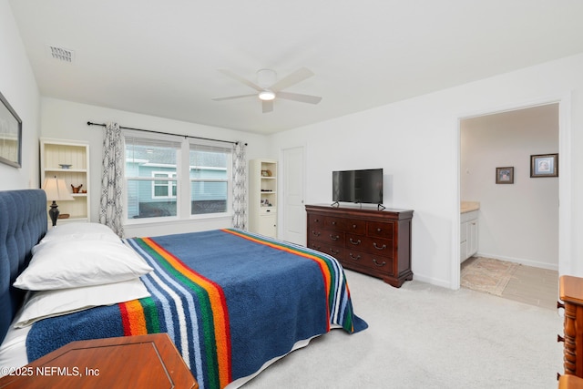 bedroom featuring ensuite bath, light colored carpet, and ceiling fan