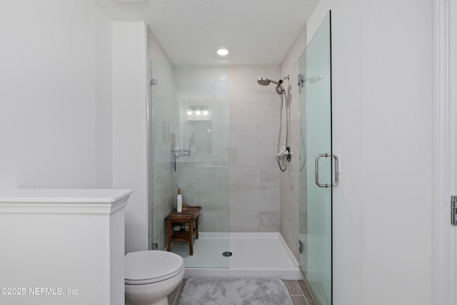 bathroom featuring a shower with door and toilet