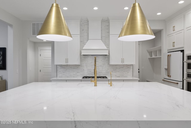 kitchen featuring light stone counters, backsplash, and custom exhaust hood