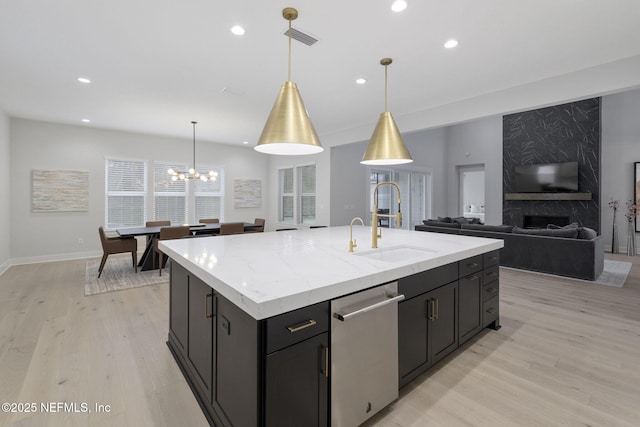 kitchen with pendant lighting, dishwasher, sink, and a center island with sink