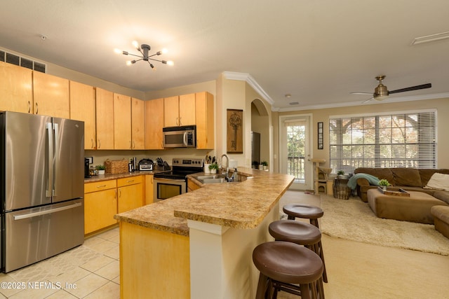 kitchen featuring stainless steel appliances, a breakfast bar, light brown cabinetry, and kitchen peninsula