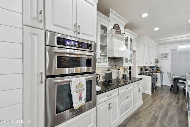 kitchen with white cabinetry, dark hardwood / wood-style flooring, black electric stovetop, and double oven