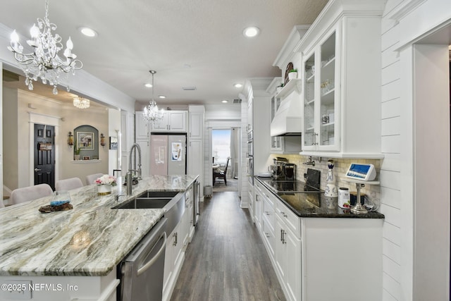 kitchen featuring white cabinetry, a chandelier, hanging light fixtures, dark stone countertops, and stainless steel dishwasher