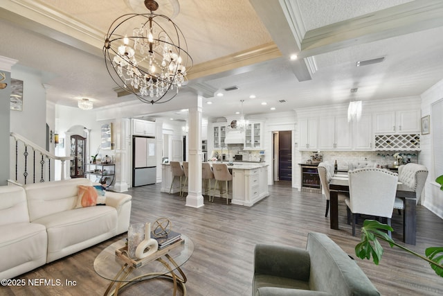 living room with dark hardwood / wood-style floors, beam ceiling, ornamental molding, coffered ceiling, and an inviting chandelier