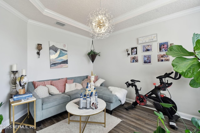 living room with dark hardwood / wood-style flooring, a notable chandelier, ornamental molding, and a textured ceiling