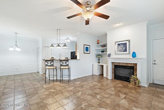 living room with crown molding, ceiling fan, built in features, and a fireplace