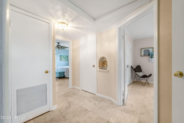 hallway with ornamental molding and a textured ceiling