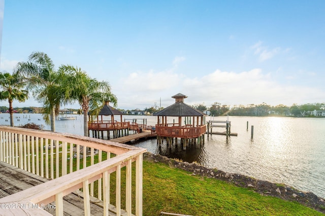 dock area with a gazebo, a water view, and a lawn