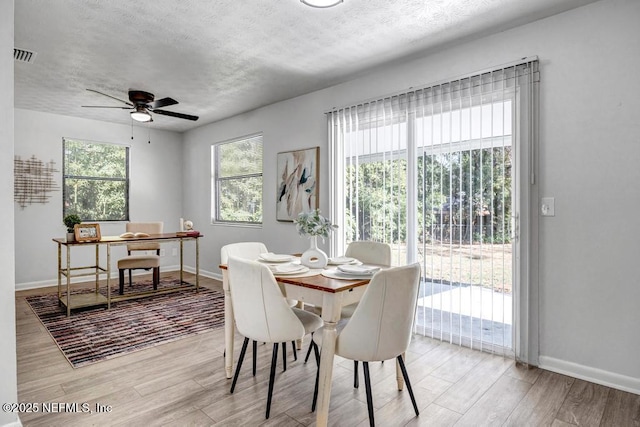 dining area with a textured ceiling, ceiling fan, and light hardwood / wood-style flooring