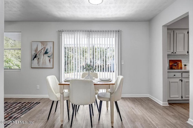 dining area with plenty of natural light, light hardwood / wood-style flooring, and a textured ceiling