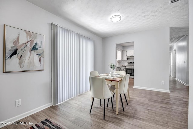 dining area with sink, a textured ceiling, and light wood-type flooring