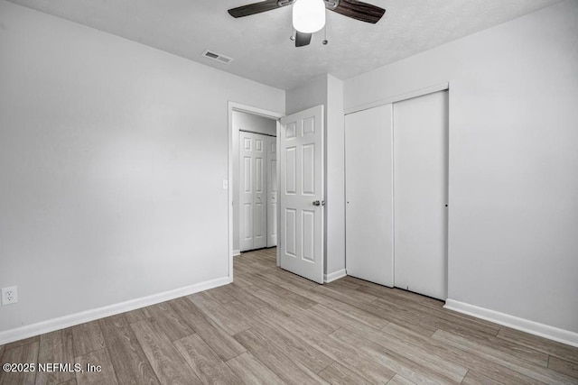 unfurnished bedroom with ceiling fan, a closet, and light wood-type flooring