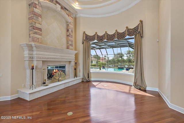 interior space featuring hardwood / wood-style floors, a premium fireplace, baseboards, and ornamental molding