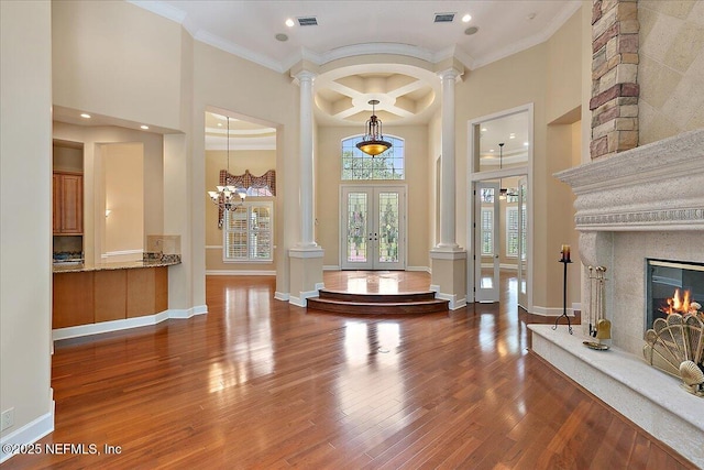 entrance foyer with french doors, a high ceiling, wood finished floors, and ornate columns