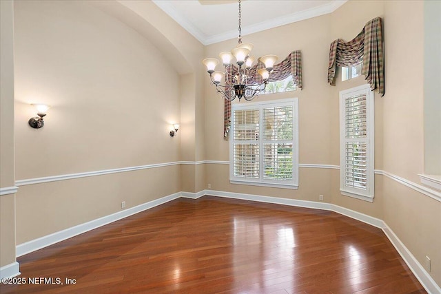 unfurnished room featuring baseboards, an inviting chandelier, ornamental molding, and hardwood / wood-style flooring