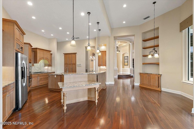 kitchen with visible vents, stainless steel fridge with ice dispenser, dark wood-style floors, arched walkways, and brown cabinetry