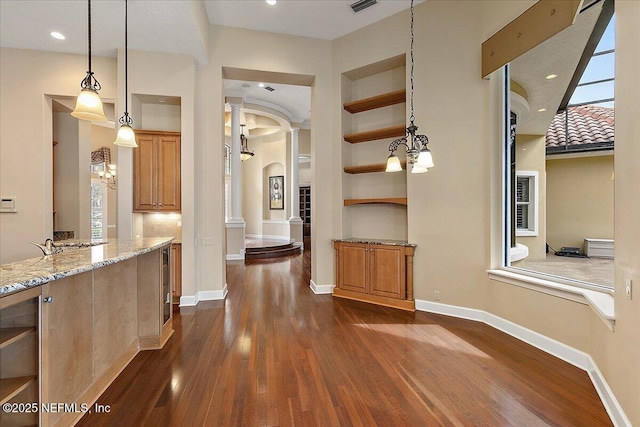 hall with dark wood-style floors, built in shelves, baseboards, and arched walkways