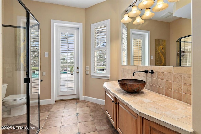 bathroom featuring tile patterned flooring, backsplash, baseboards, toilet, and vanity