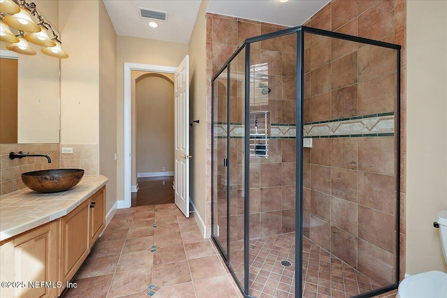 full bath featuring tile patterned floors, visible vents, toilet, a stall shower, and backsplash