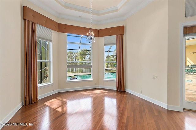 unfurnished dining area with hardwood / wood-style flooring, crown molding, baseboards, and a tray ceiling