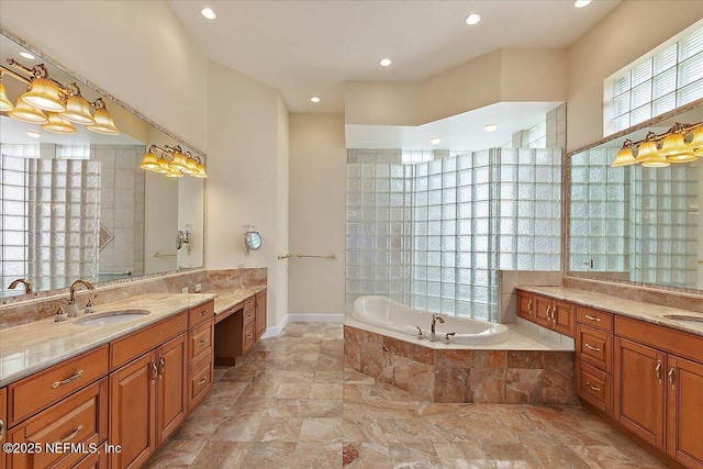 bathroom featuring two vanities, a garden tub, and a sink