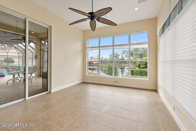 empty room with light tile patterned floors, a ceiling fan, baseboards, and a sunroom