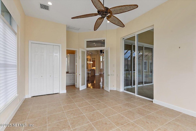 interior space with access to exterior, visible vents, baseboards, light tile patterned floors, and a ceiling fan