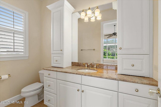 bathroom with vanity, toilet, baseboards, and ceiling fan