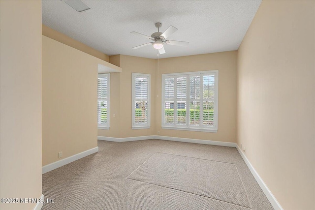 carpeted spare room with visible vents, ceiling fan, a textured ceiling, and baseboards