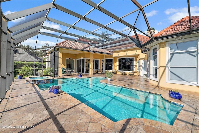 view of pool featuring glass enclosure, a pool with connected hot tub, and a patio area