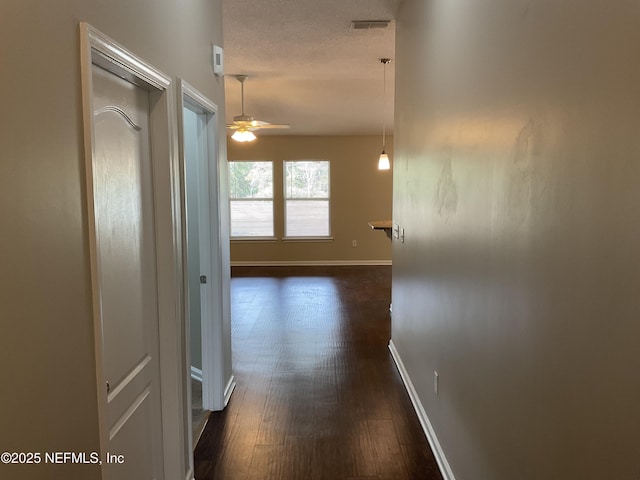 corridor featuring dark hardwood / wood-style flooring and a textured ceiling