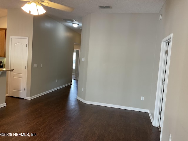 empty room featuring a high ceiling, ceiling fan, dark wood-type flooring, and a textured ceiling