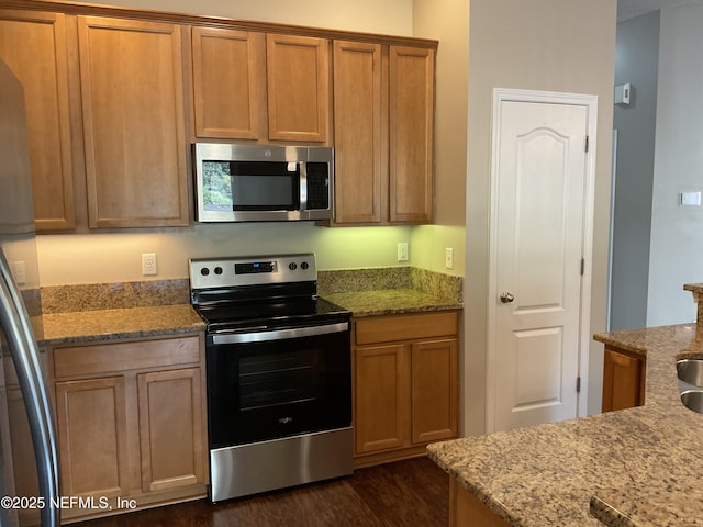 kitchen with stainless steel appliances, dark hardwood / wood-style floors, and light stone countertops