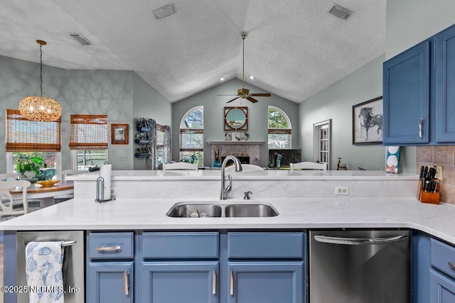 kitchen with sink, blue cabinetry, decorative light fixtures, vaulted ceiling, and stainless steel dishwasher