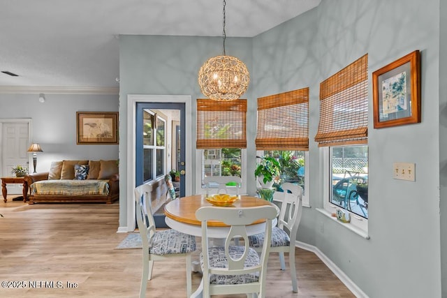 dining room featuring crown molding, an inviting chandelier, and light hardwood / wood-style floors