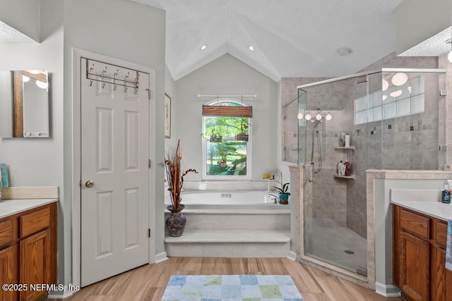 bathroom featuring plus walk in shower, lofted ceiling, hardwood / wood-style floors, and vanity