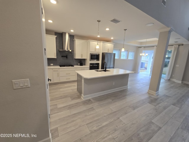 kitchen featuring visible vents, light wood-style flooring, appliances with stainless steel finishes, and wall chimney range hood